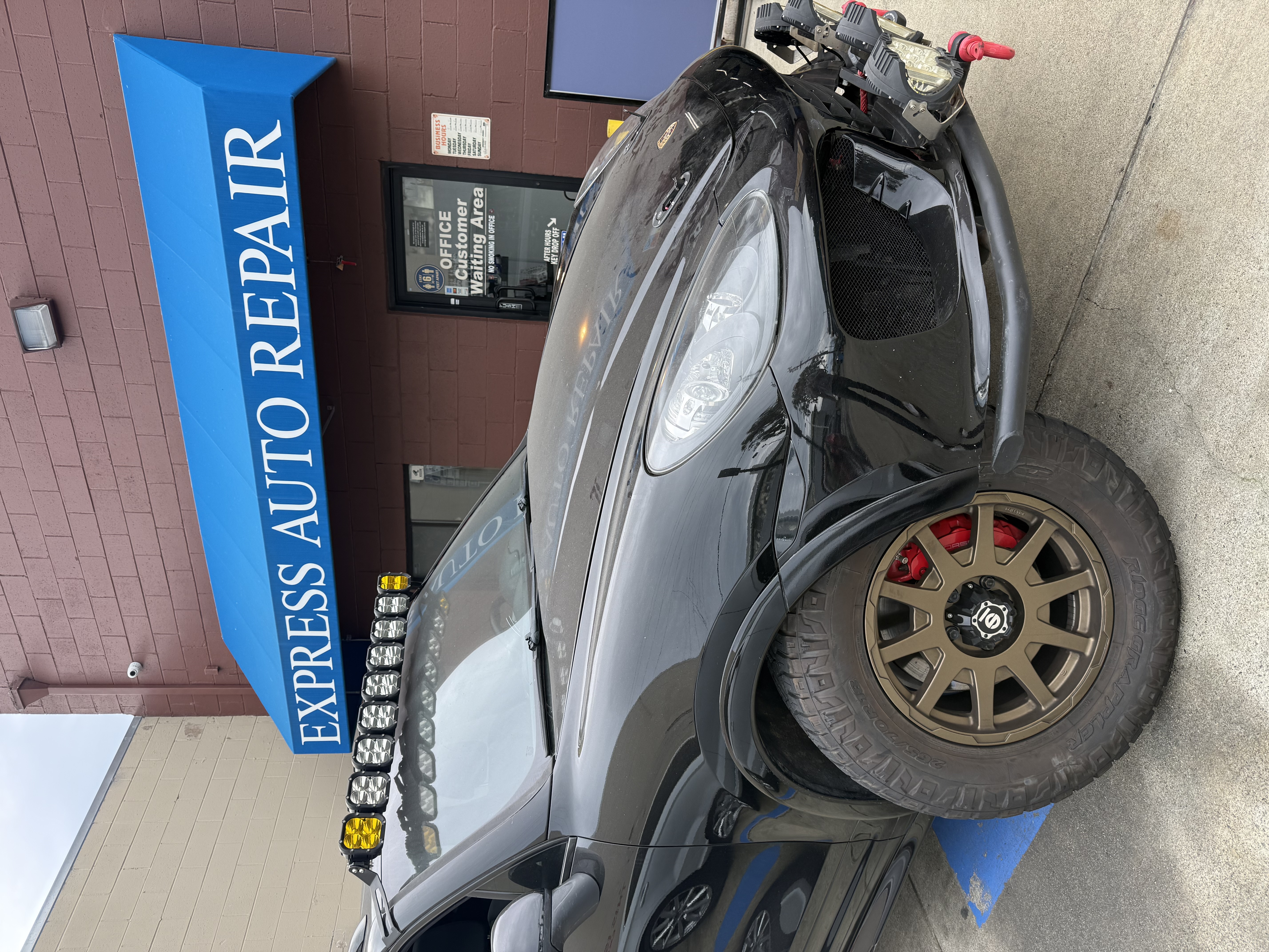 Porsche Cayenne on lift at Express Auto Repair — Tesla & German auto specialists in San Bruno CA